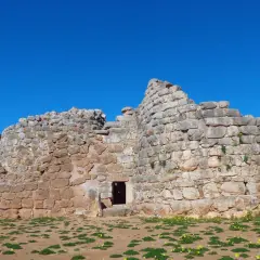 Il nuraghe Palmavera, imponente struttura in pietra sotto un cielo azzurro, testimone di antiche civiltà.