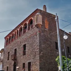 Stone building with arched balconies and a turret against a cloudy sky.