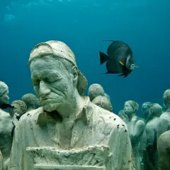 Un gruppo di statue giganti mare, con un pesce che nuota tra loro, crea un'atmosfera surreale.