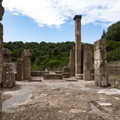 Rovine antiche con colonne di pietra e un cielo azzurro. Un luogo che evoca il mito del Sardus Pater.