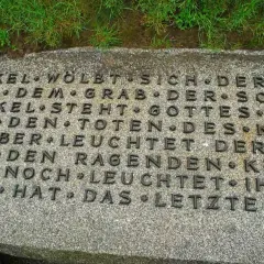 Dettaglio di un'iscrizione in tedesco su una lapide in un cimitero tedesco in Normandia. Le parole evocano oscurità e speranza.