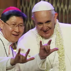 Papa Francesco e un vescovo fanno il gesto delle corna a tre dita, un segno di benedizione e speranza.