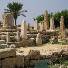 Antiche rovine con obelischi e una palma, testimonianza dei popoli del mare.