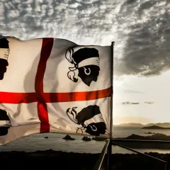 Bandiera sarda sventola al tramonto, simbolo di un'antica origine lingua sarda.