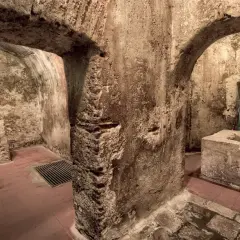 Interno dell'ipogeo San Salvatore: archi in pietra grezza, vasca in cemento, pavimenti in cotto e un antico altare.