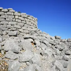 Rovine del nuraghe Barru, con pietre grigie e un cielo blu intenso.