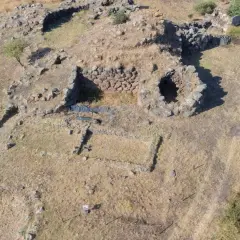 Resti di un antico villaggio nuragico, con pietre che delineano le fondamenta di antiche abitazioni e mura.