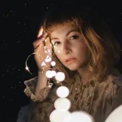 Una ragazza con luci scintillanti tra le dita, come un filo di Arianna che illumina il buio.