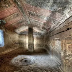 Interno di domus de janas dipinte, con pilastro centrale e decorazioni circolari sul pavimento.