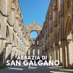L'abbazia di San Galgano, un'imponente rovina nel cuore di un querceto, si erge maestosa sotto un cielo azzurro.