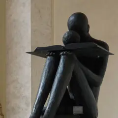 Statua di una figura che legge, immersa in un momento di riflessione, quasi un sinonimo di accidia intellettuale.