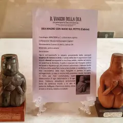 Due statue neolitiche di dea madre con le mani sul petto, una in pietra calcarea verde scuro, l'altra in terracotta.