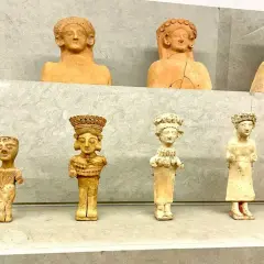 Antiche statuette in terracotta, tra cui una dea punica della fertilità, esposte su una mensola.