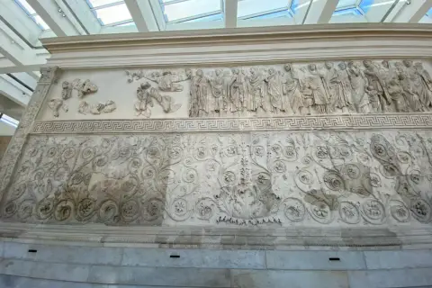 Rilievi dell'Ara Pacis: una processione di figure e decorazioni floreali intricate, testimonianza dell'arte romana.