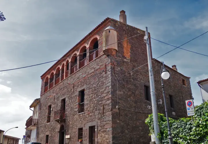 Stone building with arched balconies and a turret against a cloudy sky.