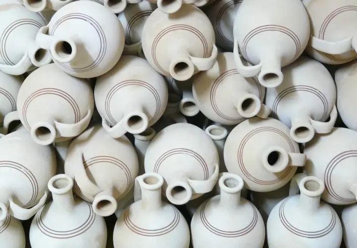 Un mucchio di giarre in terracotta, ognuna con un'ansa e due bocche, decorate con sottili linee marroni. Queste giarre, con il loro **giara significato** di contenimento e tradizione, creano un pattern visivo affascinante.