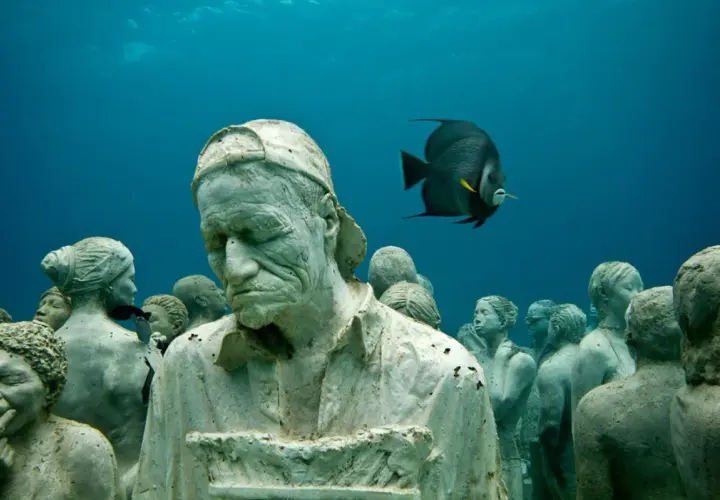 Un gruppo di statue giganti mare, con un pesce che nuota tra loro, crea un'atmosfera surreale.