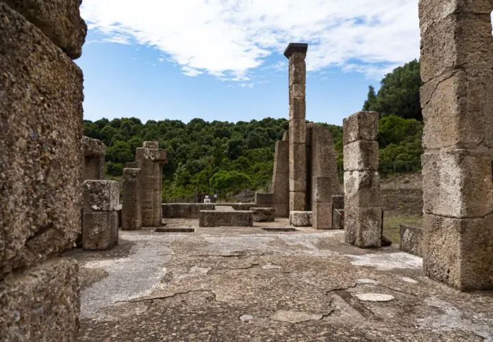 Rovine antiche con colonne di pietra e un cielo azzurro. Un luogo che evoca il mito del Sardus Pater.