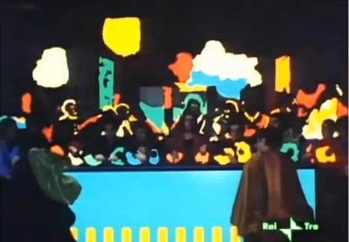 Scena colorata con figure stilizzate, forse una rappresentazione teatrale. Si intravede un personaggio con un mantello marrone, forse **Salomé**, bene in vista.