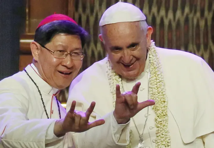 Papa Francesco e un vescovo fanno il gesto delle corna a tre dita, un segno di benedizione e speranza.