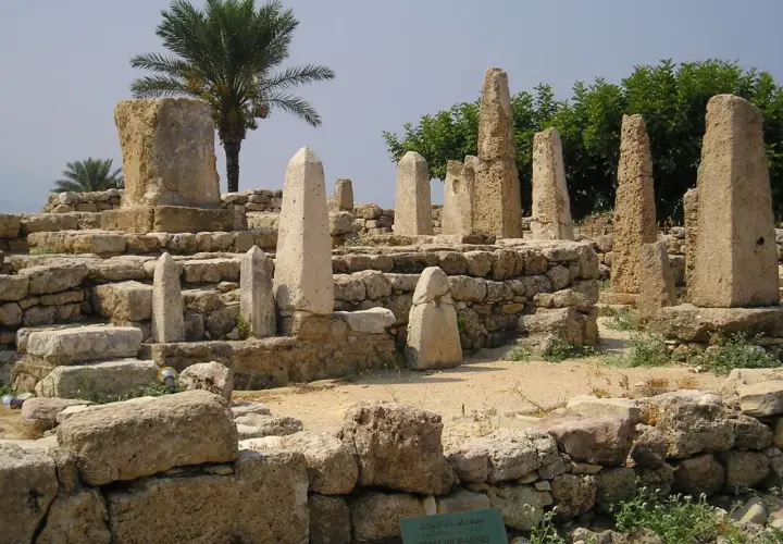 Antiche rovine con obelischi e una palma, testimonianza dei popoli del mare.