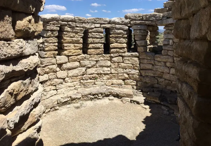 Interno del nuraghe Su Mulinu, con mura in pietra grezza e finestre quadrate che si affacciano sul paesaggio.