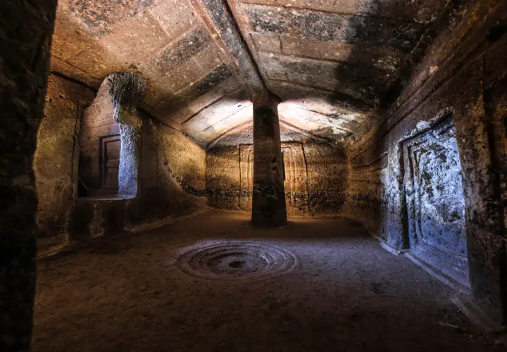 Interno di una domus de janas a Putifigari, con pilastro centrale e decorazioni scolpite.