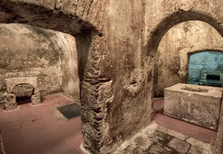 Interno dell'ipogeo San Salvatore: archi in pietra grezza, vasca in cemento, pavimenti in cotto e un antico altare.