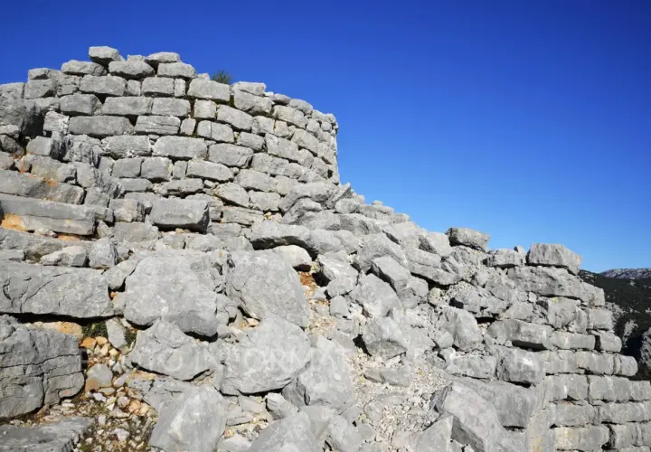 Rovine del nuraghe Barru, con pietre grigie e un cielo blu intenso.