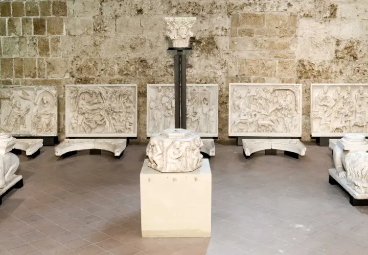 Sculture in pietra bianca, tra cui leoni stilofori e rilievi narrativi, forse frammenti di un antico pergamo, evocano un profondo significato storico e artistico.