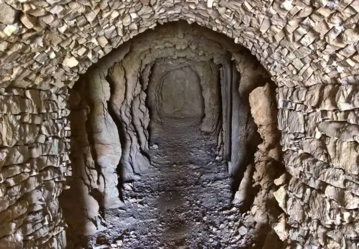 Un tunnel scavato nella roccia, con pareti in pietra grezza e un soffitto a volta. Un luogo che evoca il ricordo dei caduti della Prima Guerra Mondiale.