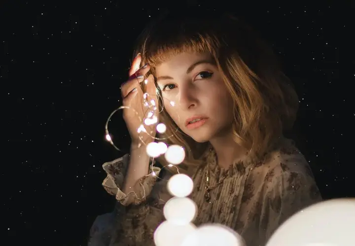 Una ragazza con luci scintillanti tra le dita, come un filo di Arianna che illumina il buio.
