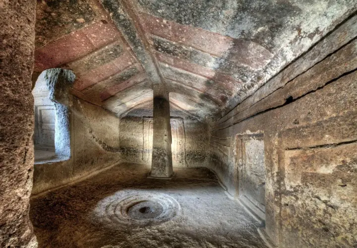 Interno di domus de janas dipinte, con pilastro centrale e decorazioni circolari sul pavimento.