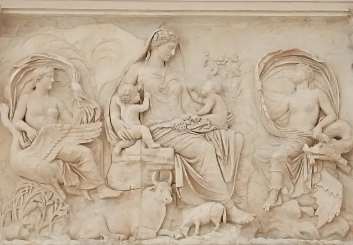 Rilievo esterno dell'Ara Pacis: una madre con due bambini, affiancata da figure femminili con cigno e creatura marina, circondata da animali e vegetazione.