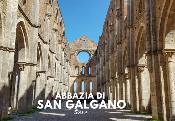 L'abbazia di San Galgano, un'imponente rovina nel cuore di un querceto, si erge maestosa sotto un cielo azzurro.