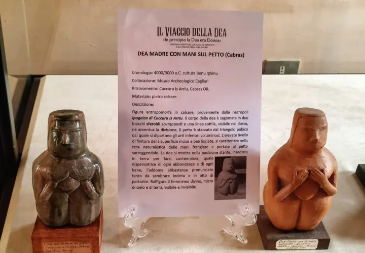 Due statue neolitiche di dea madre con le mani sul petto, una in pietra calcarea verde scuro, l'altra in terracotta.