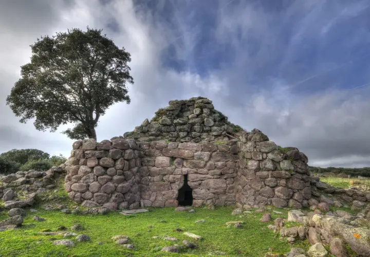 Il nuraghe Appiu, con la sua imponente struttura in pietra, si erge solitario sotto un cielo nuvoloso, testimone di antiche storie.