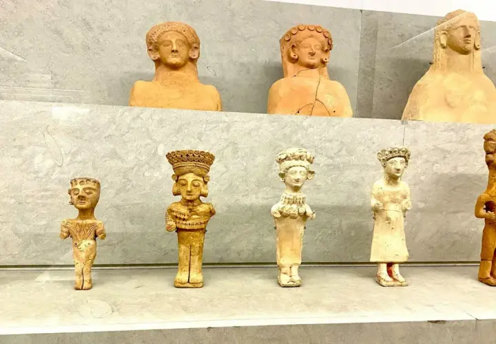 Antiche statuette in terracotta, tra cui una dea punica della fertilità, esposte su una mensola.