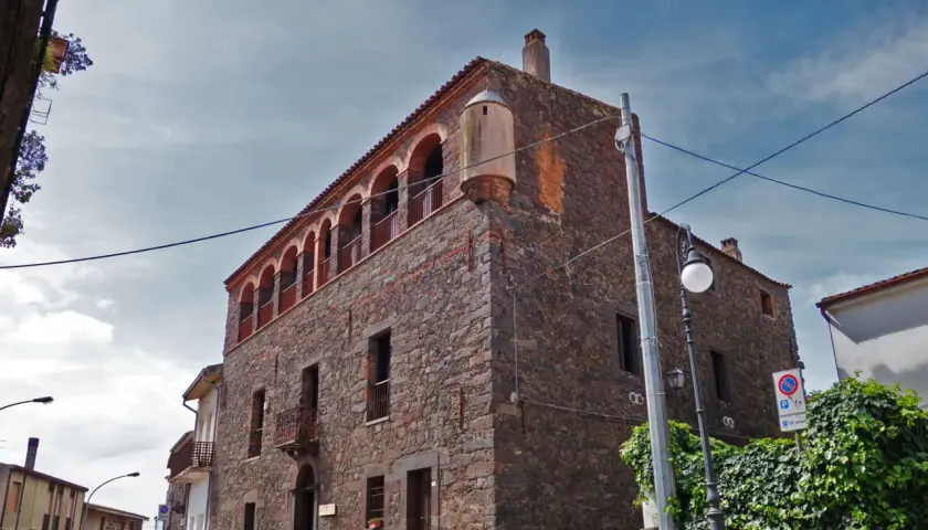 Stone building with arched balconies and a turret against a cloudy sky.