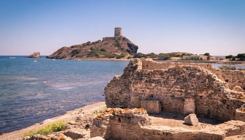 Rovine antiche sulla costa sarda, con una torre in lontananza. Un pezzo di storia della Sardegna che emerge dal passato.