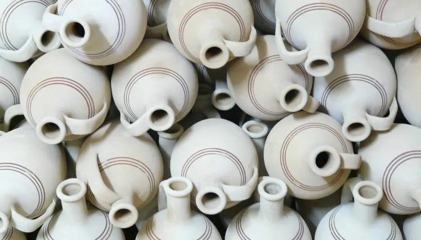 Un mucchio di giarre in terracotta, ognuna con un'ansa e due bocche, decorate con sottili linee marroni. Queste giarre, con il loro **giara significato** di contenimento e tradizione, creano un pattern visivo affascinante.