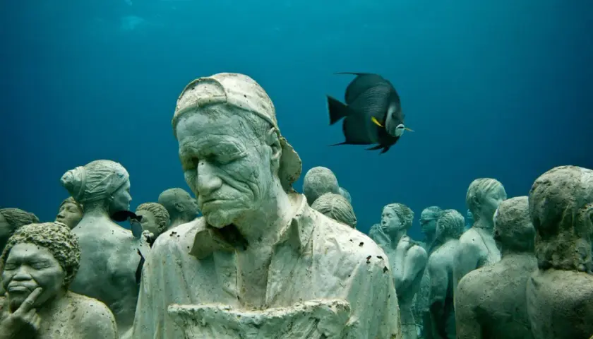 Un gruppo di statue giganti mare, con un pesce che nuota tra loro, crea un'atmosfera surreale.