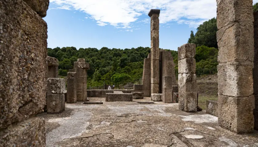 Rovine antiche con colonne di pietra e un cielo azzurro. Un luogo che evoca il mito del Sardus Pater.