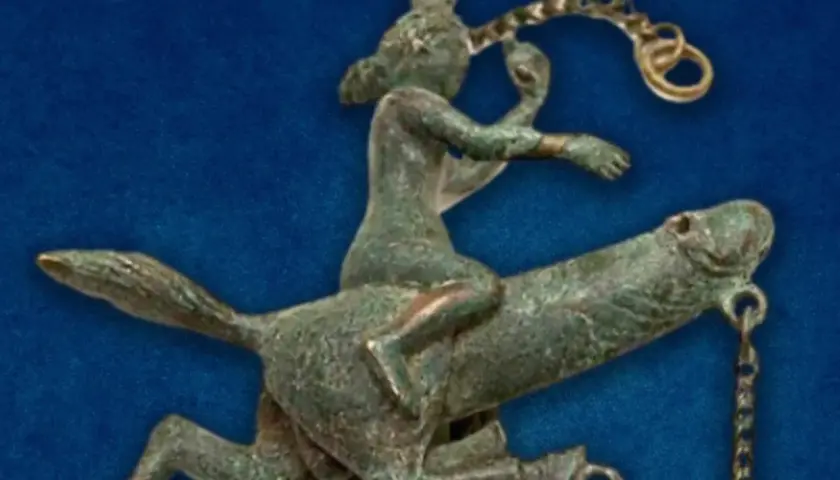 Antica statuetta in bronzo di un cavaliere che cavalca un cavallo, forse un **fallo dio pan** in movimento.