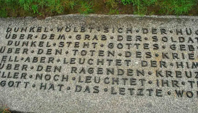 Dettaglio di un'iscrizione in tedesco su una lapide in un cimitero tedesco in Normandia. Le parole evocano oscurità e speranza.