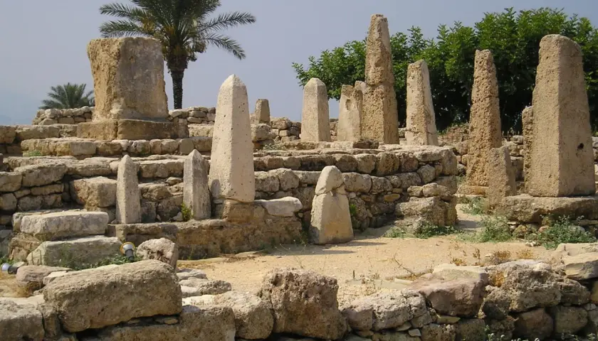 Antiche rovine con obelischi e una palma, testimonianza dei popoli del mare.