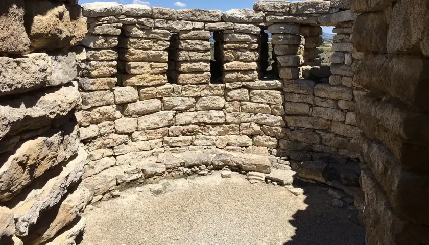 Interno del nuraghe Su Mulinu, con mura in pietra grezza e finestre quadrate che si affacciano sul paesaggio.