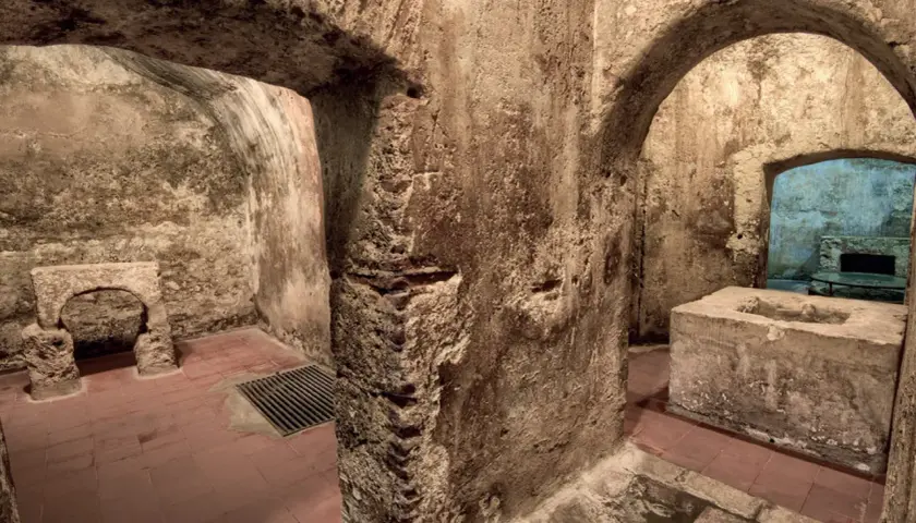 Interno dell'ipogeo San Salvatore: archi in pietra grezza, vasca in cemento, pavimenti in cotto e un antico altare.