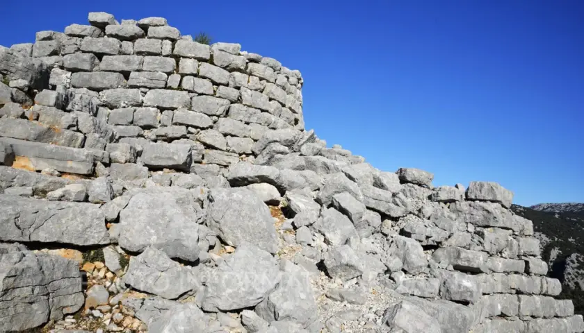 Rovine del nuraghe Barru, con pietre grigie e un cielo blu intenso.