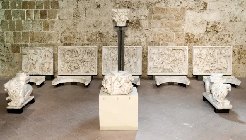 Sculture in pietra bianca, tra cui leoni stilofori e rilievi narrativi, forse frammenti di un antico pergamo, evocano un profondo significato storico e artistico.